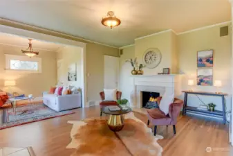 Expansive living area with original hardwood floors, gas fireplace, and crown molding.