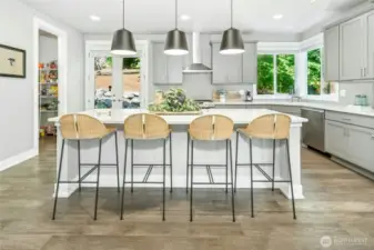 The large gourmet kitchen features quartz countertops, an oversized island with seating, stainless steel appliances, and a walk-in pantry for ample storage.