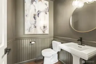 The updated half bath, off the foyer, features wainscotting, black matte and brushed gold finishes.