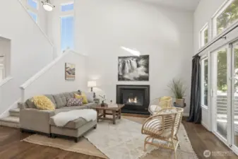 The comfortable living room featuring hardwood floors and walls of windows, is a magnificent place to entertain or cozy up next to the gas fireplace.