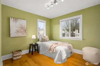 The second bedroom feels fresh and calming, painted a lovely lichen green and filled with natural light from double windows that make the space feel bright and uplifting.