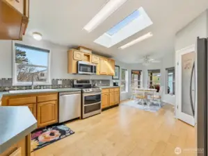 oak cabinetry and large windows overlooking the backyard. Well taken care of appliances and skylights bring ample light.