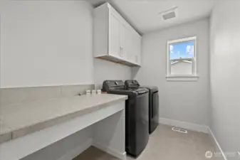 Upstairs laundry room with counterspace and storage.