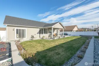 Back yard features include a masonry terrace, level lawn and fully-irrigated landscape surrounded by vinyl fencing.