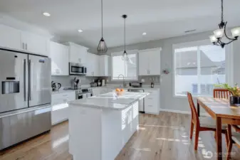 Bright, gleaming kitchen boasts Bosch appliances, quartz counters, plank floors and slow-close drawers.
