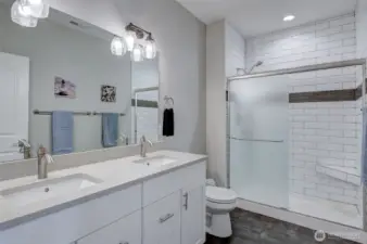 Stylish primary bathroom includes quartz double vanity and custom walk-in shower.
