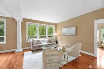 Elegant formal living room filled with natural light—perfect for after-dinner conversations, quiet reading, or your cocktail hour gatherings. Framed by architectural columns and large picture windows overlooking the private side yard.