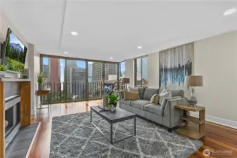 Sunlit living room with floor-to-ceiling windows, cozy fireplace, and sweeping city and water views.