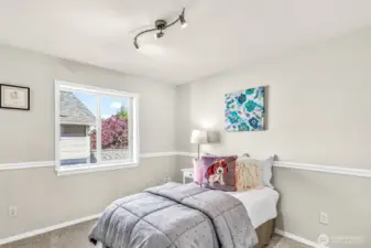Another upstairs bedroom adds flexibility—note the chair-rail detail and updated ceiling fixture. Soft new carpet and a calm palette create a restful, ready-to-use space.