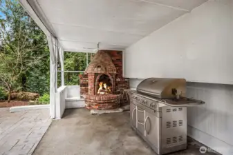 Covered outdoor entertaining area with grill and fireplace.