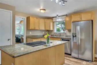 Island kitchen with slab granite and stainless appliances is perfectly located between the dining room and the family room.