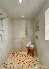 A walk-in shower with floor to ceiling marble walls and tile floor.