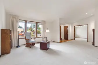 A view from the dining room into the living room and entry showing the double doors into the office and also show casing the vaulted ceiling.