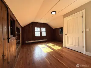 Upstairs bedroom 2 with hardwood floors, real wood wall coverings, and lots of natural light.