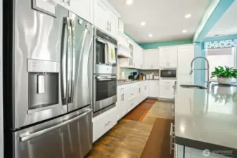 Gourmet kitchen with gas cooktop, double wall oven, french door refrigerator, stainless appliances, slab quartz countertops, center island eating bar that opens to the great room (living and dining rooms).