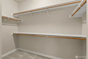 Primary walk-in closet boasts of hanging space and solid wood shelving.