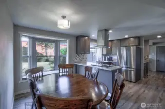 View of eating area with a large bay window looking into the spacious backyard and kitchen from hall that leads to the bedrooms