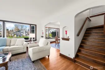 Staircase & Loft Access: The living area flows seamlessly toward a classic wooden staircase leading to the upper-level bedrooms and loft, highlighting the home's functional and open layout.