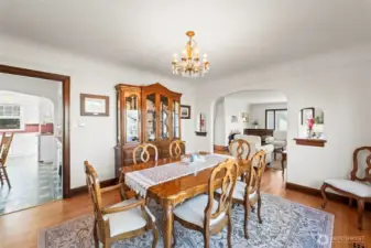 Formal Dining Room: Host memorable gatherings in this grand dining room. It features a vintage-style chandelier, large windows overlooking the yard, and a wide arched opening that connects to the living area.