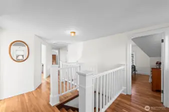 Oak Hardwood Landing: The upstairs landing showcases continuous oak hardwood flooring and a classic white banister, leading to the private upper-level quarters in an open, airy layout.