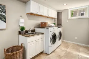 Just off the hallway and lower garage is this enormous laundry room with laundry sink, overhead cabinets and tiled floor.