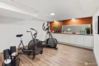 This adaptable basement room features a long counter with ample cabinetry underneath, providing an ideal setup for a home workshop or hobby space. The generous counter space and storage options make it perfect for DIY projects, crafts, or tool organization, catering to various creative or practical pursuits.