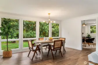 Expansive floor-to-ceiling windows flood the formal dining area with natural light and offer a seamless connection to the lush outdoor setting. A window on the adjacent wall will offer a cool cross breeze in the summertime. The modern chandelier adds a stylish touch, while the spacious layout is perfect for gatherings and special occasions.