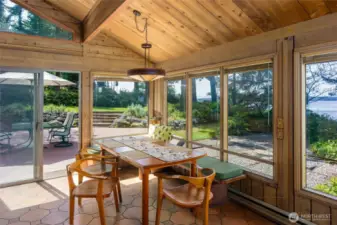 Walls of windows surround the dining area overlooking the patio, deck and beyond to the Channel.