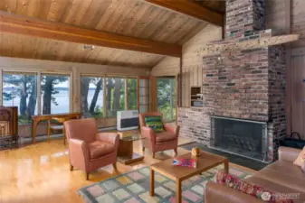Vaulted ceilings open to walls of windows and the brick fireplace.
