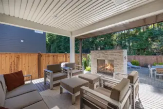 The backyard features a covered porch, thoughtfully designed with recessed lighting, built-in speakers, and outdoor fireplace with Eldorado Stone finish for year-round comfort.