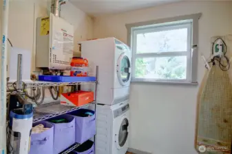 Laundry/mud room with stack washer/dryer, tankless water heater and storage.