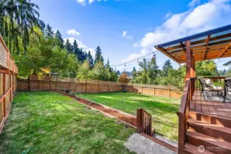 Large fenced backyard with new flower beds.