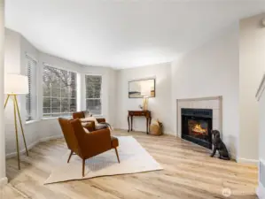 The entry way opens to the living room with its large windows and wood burning fireplace