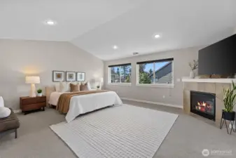 Expansive primary suite with vaulted ceilings, cozy gas fireplace, and large windows, offering a peaceful retreat within this Lynnwood home.