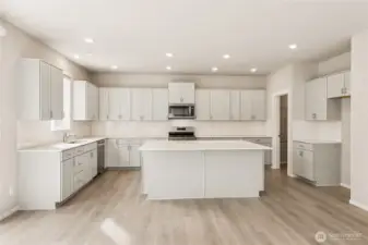 Chef's kitchen with shaker-style cabinetry, white quartz countertops, a large center island with bar seating, stainless steel appliances. Photos are representative only and may display different color package and/or upgrades.
