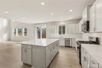 Kitchen from a second angle showcasing the center island with quartz countertop, full stainless steel appliance suite including range, microwave, and dishwasher. Photos are representative only and may display different color package and/or upgrades.