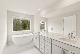 Luxurious primary en-suite bathroom featuring a freestanding soaking tub beneath a large window. Photos are representative only and may display different color package and/or upgrades.