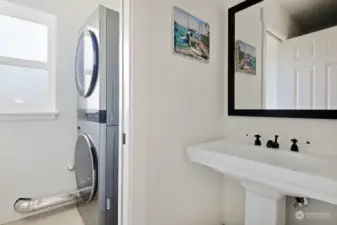 Half bath with washer & dryer beyond. There is a pocket door between the 1/2 bath and washer & dryer. Ceramic tiled floors.
