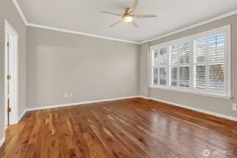 Main floor primary with wood floors and plantation shutters