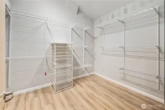 Custom walk-in closet with adjustable shelving, hanging systems, new flooring, bright lighting, and efficient, organized storage design. Private safe.