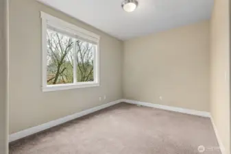 This main room with closet gives your 5th bedroom option is one of those spaces you’re glad you have. At roughly 11’ by 16’, it’s generously sized and gets great light from a large window with blinds, plus a treetop view that adds a little calm to the day. Muslin toned walls and neutral carpeting keep it flexible and easy to style. Guest room, second office, hobby space, or that bonus bedroom everyone is happy to have on the main floor.