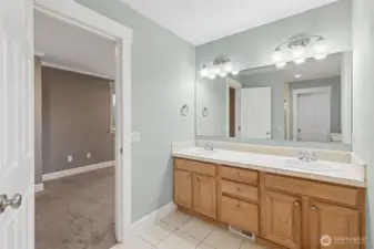 The primary bathroom keeps things simple and well done with a dual sink vanity with shaker cabinetry gives you storage and elbow room, while the oversized mirror and globe style sconces add brightness without glare. Tile floors stay practical, and the soft dove gray walls create a relaxed, neutral backdrop that works with any style.