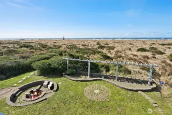 The backyard with a sunken fire pit, pergola, cobblestone and stepping stones to the beach trail.