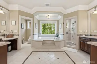 Double doors to the travertine bathroom with separate vanities, thick crown molding, travertine shower with multiple shower heads, heated travertine floors and air jetted 2 person tub.
