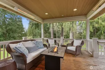 Covered deck off the kitchen with heaters and an outdoor kitchen, stairs down to the yard.