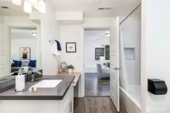 Full bath on lower level is very spacious (photo taken in front of washer & dryer area which includes more storage shelving, looking back out toward living room).