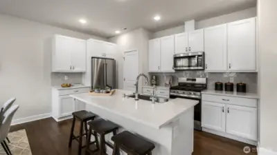 Well-appointed kitchen features under cabinet lighting, soft-close drawers and cabinet doors, tap-on kitchen faucet, pantry, and quartz countertops