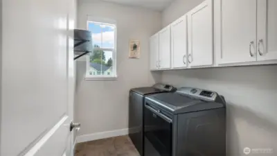Convenient laundry room located on the upper level features Maytag washer and dryer. Shelving and cabinets provide extra storage.