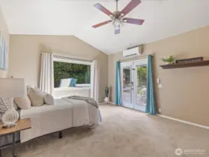French doors open to a paver patio with hot tub, filling the primary suite with natural light. A mini-split AC/heat unit ensures year-round comfort, and plush carpeting adds a cozy touch underfoot.