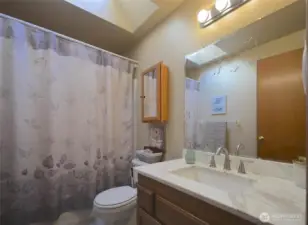 The two bedrooms share the common bath. The floor is tiled, there's a quartz counter with an undermount sink. A large skylight brightens up the space.